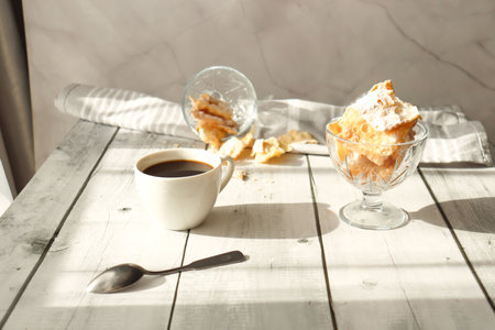 Cup of coffee and cookies on white wooden table, closeup