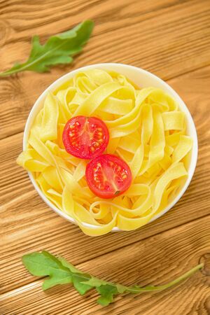 ready-made spaghetti tagliatelle with cherry tomato and arugula on a wooden background. Close-upの写真素材