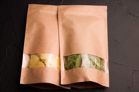pineapple and kiwi fruit chips in paper packaging on a black backgroundの写真素材
