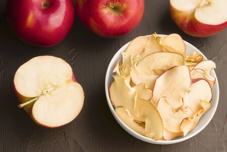 fruit apple chips in a white plate on a black background. next to a fresh apple. Natural snacksの写真素材