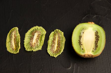 Kiwi fruit chips on a black background next to fresh kimi. fruit snacksの写真素材