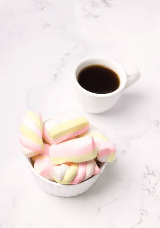 Cup of coffee next to marshmallows on a marble tableの写真素材