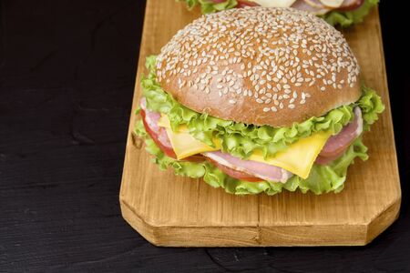 sandwich with bacon, herbs, tomato and cheese on a wooden board on a black backgroundの写真素材