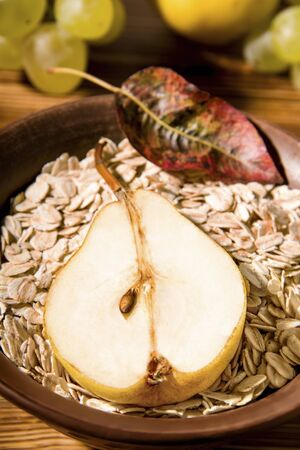 plate with oatmeal and half a pear. Autumn breakfast on burnt woodの写真素材