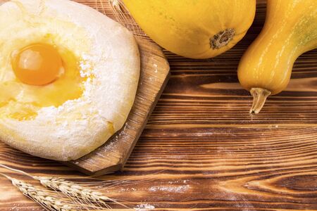 Uncooked dough on a wooden board next to pumpkins. Rustic cooking processの写真素材