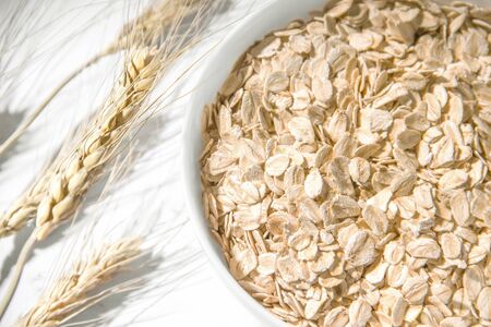 dry oatmeal in a plate with ears of wheat.