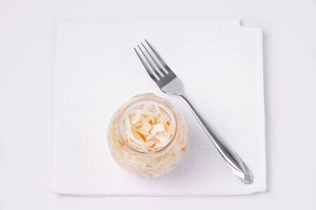 Pickled cabbage with carrots in a jar on a white background, next to a fork. Fermented vegetablesの写真素材