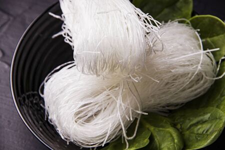 Asian food. Noodles in a black plate with herbs. Not ready funcheza.の写真素材