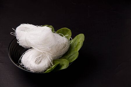 Asian food. Noodles in a black plate with herbs. Not ready funcheza.copy spaceの写真素材