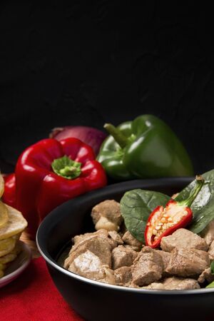 a meat dish next to vegetables in a pan on a black background. have copy spaceの写真素材