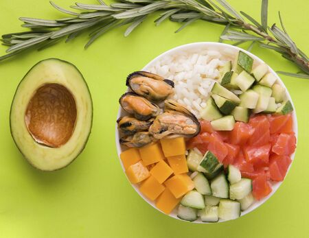 poke salad on a green background close-up next to half an avocadoの写真素材