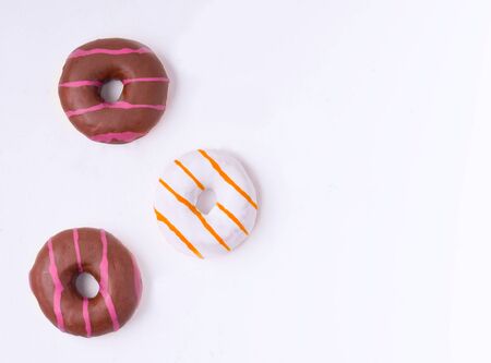 Three donuts in chocolate and vanilla glaze on a white background with place for textの写真素材