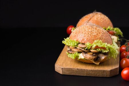 vegetarian mushroom sandwich close-up on a black background. next to the tomatoes. Have copy spaceの写真素材