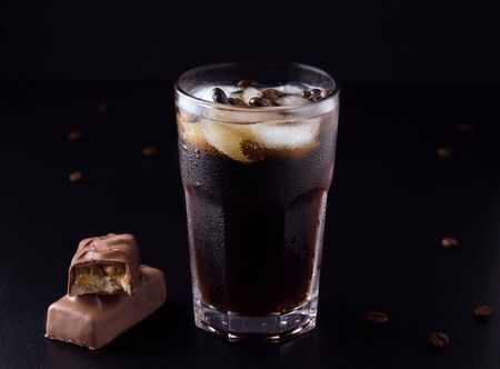 iced coffee on a black background next to coffee beans with a chocolate barの写真素材