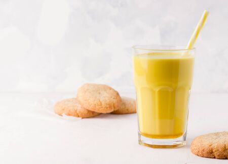 a glass of golden milk on a white background next to cookies. Traditional healthy indian drink. there is a place for textの写真素材
