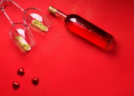 Layout with copy space on a red background with glasses filled with sparkles, wine and chocolates. Women's Day or Valentine's Day conceptの写真素材