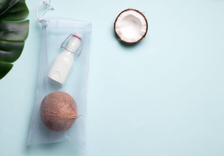 coconut milk in a bottle and an eco bag next to fresh coconut on a blue background. copy spaceの写真素材