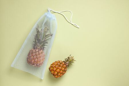 Fresh pineapple in an eco bag on a green background. copy spaceの写真素材