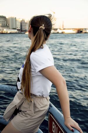 photo of a young girl on the shore facing the sea without a face.の写真素材