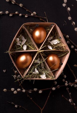 Easter eggs in a box with hay on a black background. vertical imageの写真素材