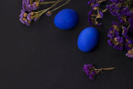 Classic blue Easter eggs on a black background with purple flowers. copy spaceの写真素材