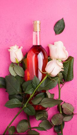 wine with white fresh roses on a pink background. Vertical imageの写真素材