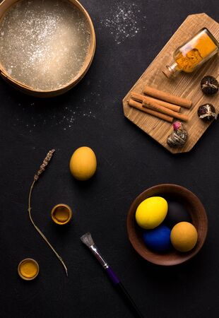 painted Easter eggs in yellow, blue and black on a black table. Easter cooking conceptの写真素材