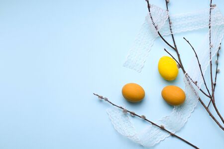 yellow easter eggs with willow branches on a blue background. There is a place for textの写真素材