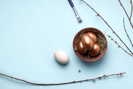 Easter wooden eggs in the process of painting in copper color on a blue background. have copy spaceの写真素材