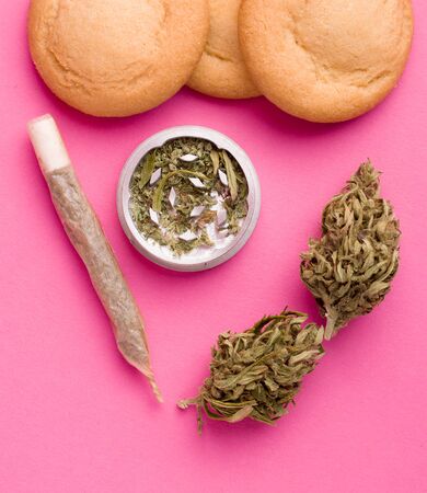 dry marijuana next to sweet cookies on a pink backgroundの写真素材