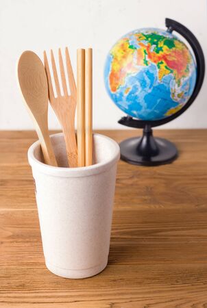 wooden utensils in a glass of metal straw on a background of the globe. zero waste conceptの写真素材