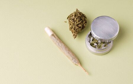 dry marijuana next to shredded and a hemp cigarette on a green background. copy spaceの写真素材