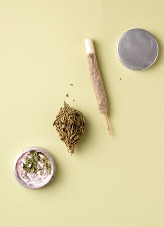 on a green background a cigarette with hemp, a branch of marijuana and a gridderの写真素材