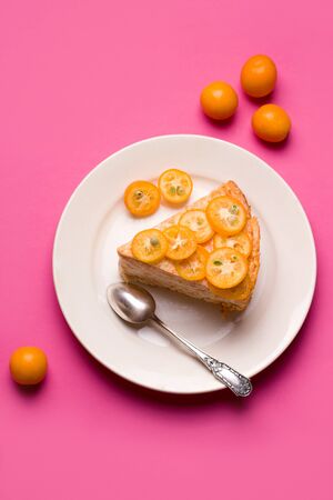 dessert sweet cake decorated with slices of tropical citrus fruit kumquat on a pink background vertical photoの写真素材