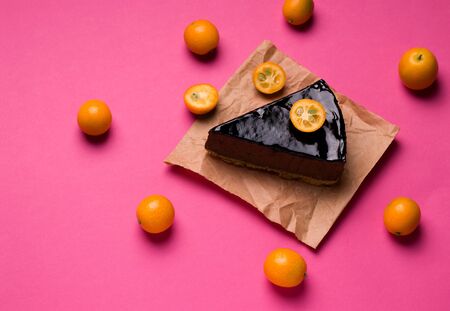 dessert sweet chocolate cake on a pink background decorated with kumquatの写真素材