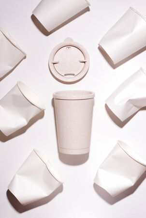 reusable coffee cup made of straw on a white background next to paper cups. monochrome patternの写真素材