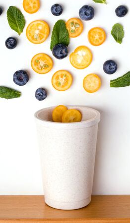 Reusable cup in which slices of fruit, berries and mint fall.の写真素材