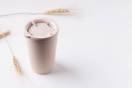 Reusable cup on a white background next to the spikelets of wheat. copy spaceの写真素材