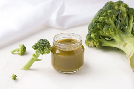 homemade mashed potatoes in a jar on a white plate next to fresh broccoli. concept of healthy, natural baby foodの写真素材