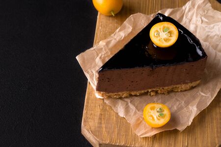 sweet chocolate cake decorated with kumquat on a black background. copy spaceの写真素材