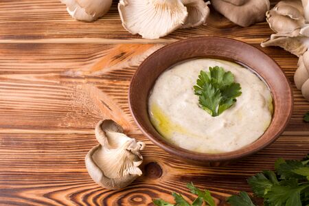 mushroom cream oyster soup on a wooden table next to fresh mushrooms. copy spaceの写真素材