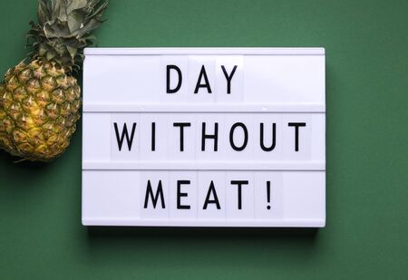 on a green background there is a lightbox with text and a fruit announcement next to it. International Day Without Meat conceptの写真素材