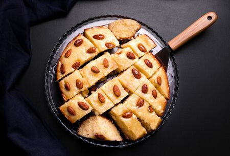 Basbus arabic pie with semolina and almonds cut into pieces on a black background.の写真素材