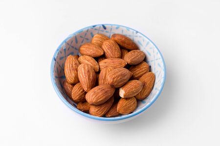 almonds in a bowl on a white backgroundの写真素材