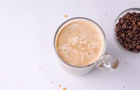 chilled coffee with cream next to coffee beans on a white background. copy spaceの写真素材