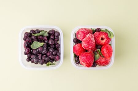 Two lunch boxes. with frozen strawberries and currants on a bright background.の写真素材