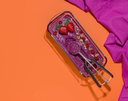 ice cream sorbet from berries with a spoon on an orange background. copy spaceの写真素材