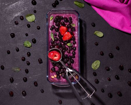 frozen berry sorbet decorated with strawberries on a black background.の写真素材