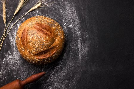 loaf of round white bread with sesame seeds and poppy seeds on a black background. copy spaceの写真素材