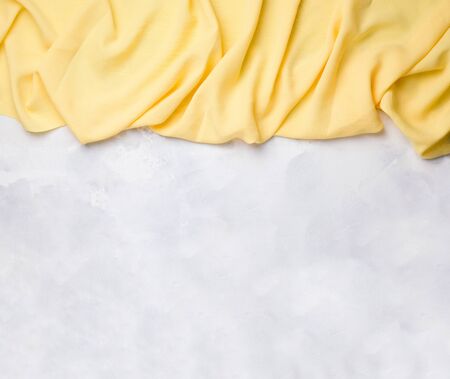 yellow fabric falling down from above on a concrete white background. copy spaceの写真素材